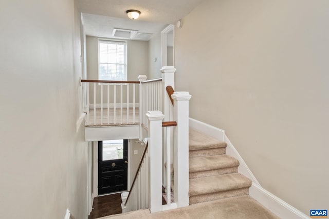 stairway featuring a textured ceiling and baseboards