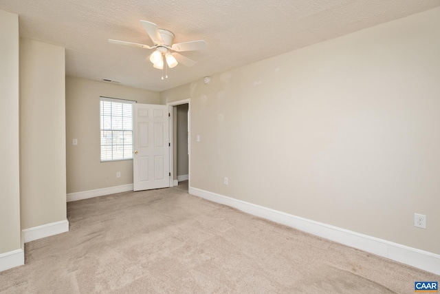 unfurnished room with a ceiling fan, baseboards, a textured ceiling, and light colored carpet