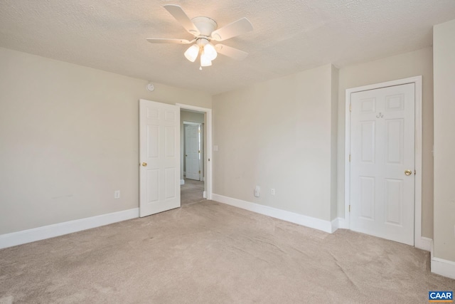 unfurnished bedroom with ceiling fan, baseboards, a textured ceiling, and light colored carpet