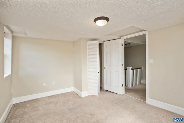 unfurnished bedroom featuring visible vents, baseboards, light colored carpet, a textured ceiling, and a closet