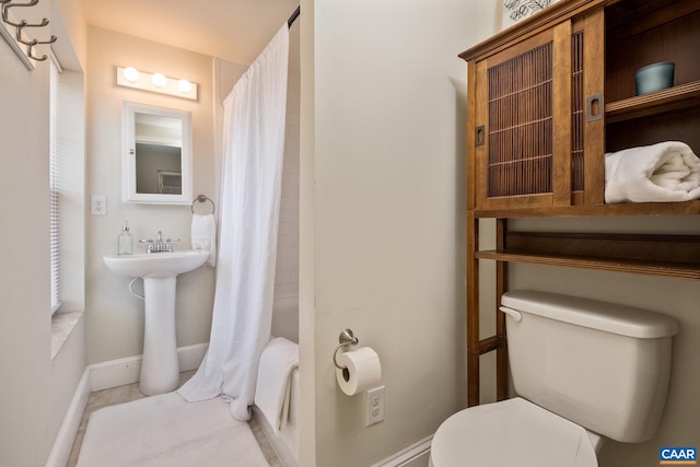 bathroom featuring toilet, a shower with curtain, and baseboards