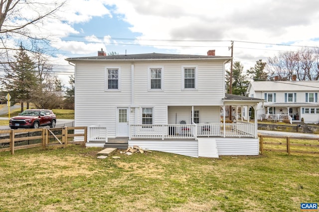 back of property with a yard, a chimney, and fence