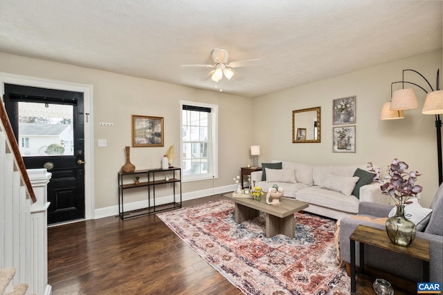 living room featuring a textured ceiling, ceiling fan, dark wood-style flooring, and baseboards