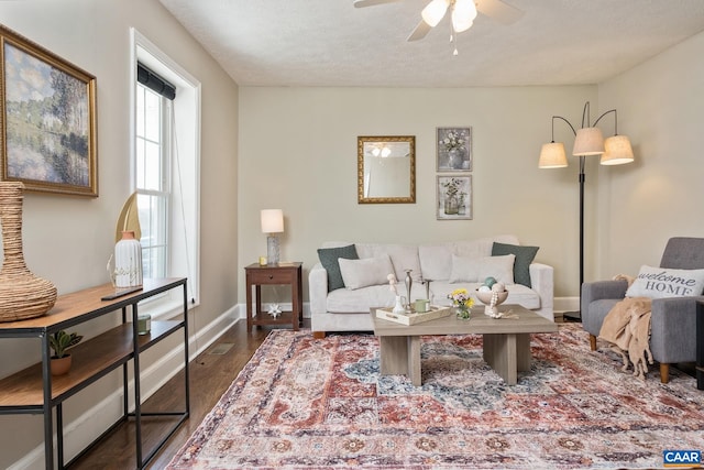 living room featuring ceiling fan, a textured ceiling, baseboards, and wood finished floors