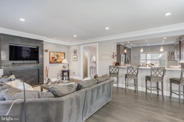 living room featuring recessed lighting, a fireplace, wood finished floors, and crown molding