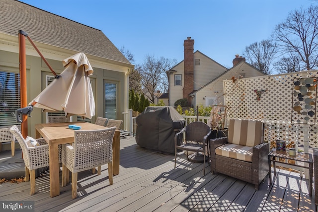 wooden deck with outdoor dining space and area for grilling