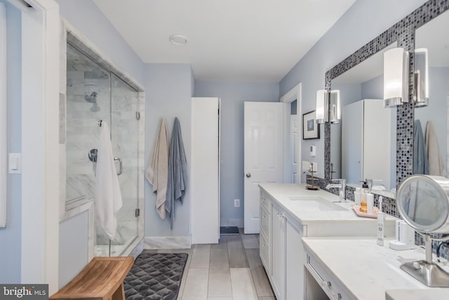 full bathroom with baseboards, a shower stall, and vanity