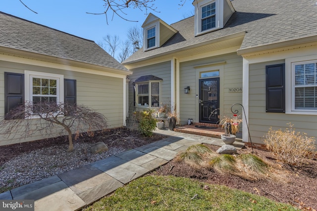 view of exterior entry with a shingled roof