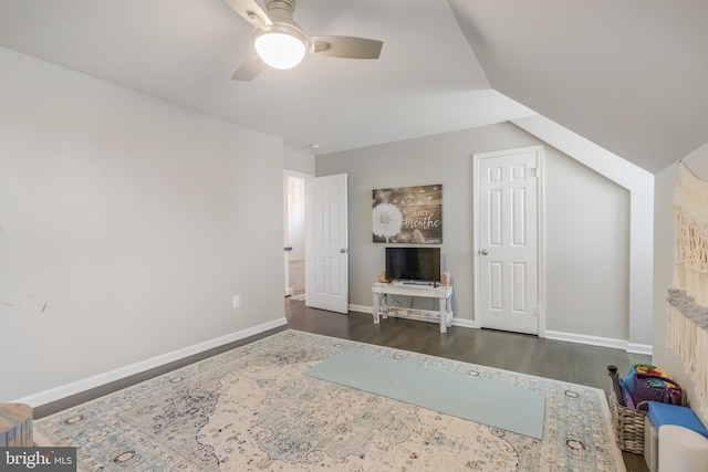 interior space featuring dark wood-style floors, lofted ceiling, a ceiling fan, and baseboards