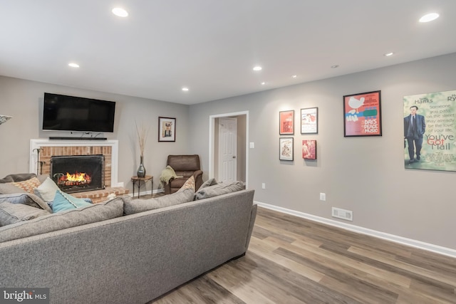 living area featuring recessed lighting, a fireplace, wood finished floors, visible vents, and baseboards