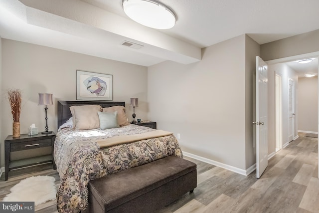 bedroom featuring light wood finished floors, visible vents, and baseboards