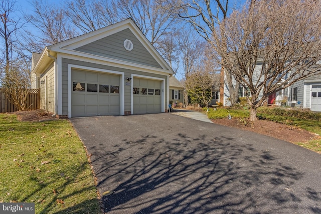 view of home's exterior with a garage, driveway, an outbuilding, and fence