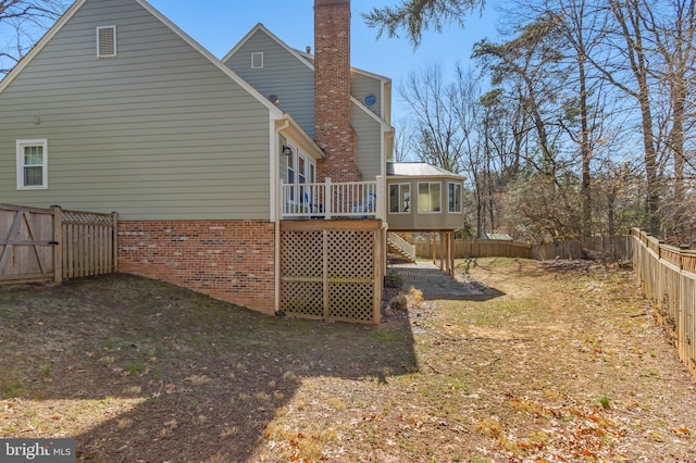 back of property featuring brick siding, a chimney, stairway, a fenced backyard, and a wooden deck