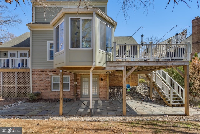 back of property featuring a patio, brick siding, a wooden deck, and a sunroom