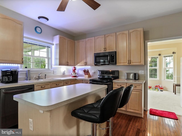 kitchen featuring black appliances, light brown cabinetry, a sink, and light countertops