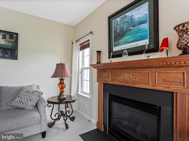 carpeted living area featuring a fireplace with flush hearth and baseboards