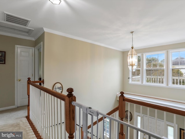 hall with a notable chandelier, visible vents, ornamental molding, light carpet, and an upstairs landing