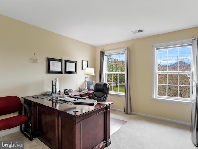 office featuring plenty of natural light, visible vents, baseboards, and light colored carpet