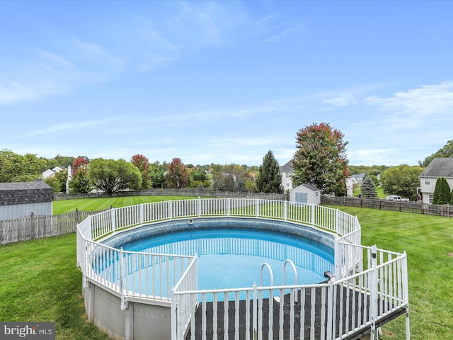 view of swimming pool featuring an outbuilding, a fenced backyard, a storage shed, a lawn, and a fenced in pool