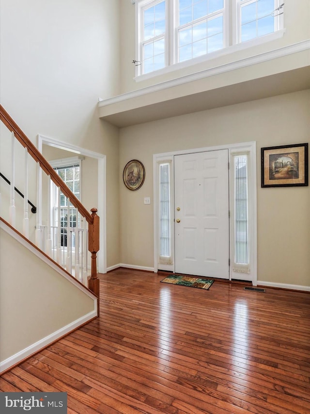 entryway with hardwood / wood-style flooring, a high ceiling, baseboards, and stairway