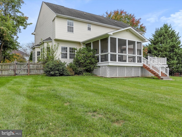 back of property with a sunroom, fence, stairway, and a lawn