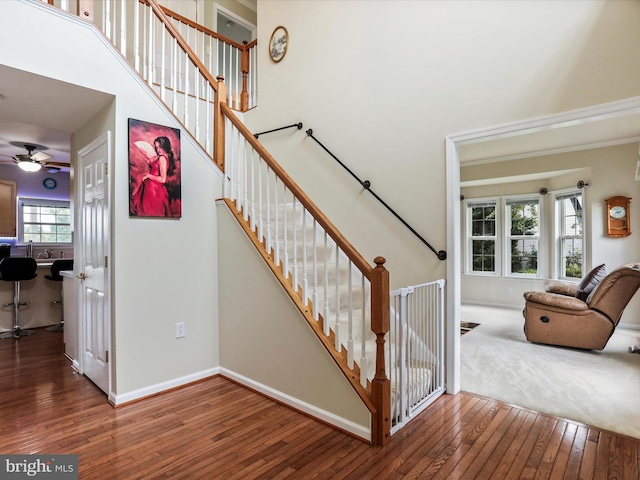 stairs with baseboards, a high ceiling, and hardwood / wood-style floors