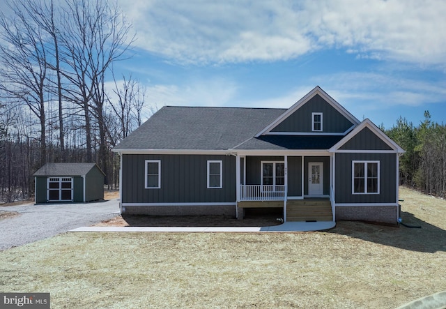 view of front facade featuring a storage unit, an outbuilding, a porch, board and batten siding, and roof with shingles