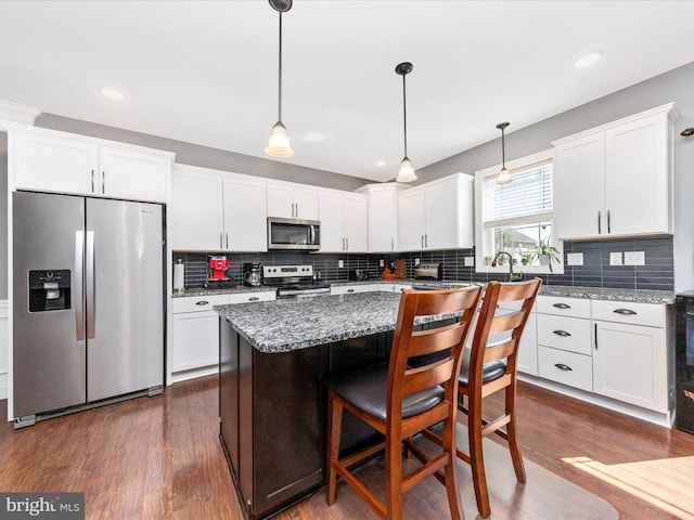 kitchen featuring dark wood finished floors, white cabinets, a center island, and stainless steel appliances