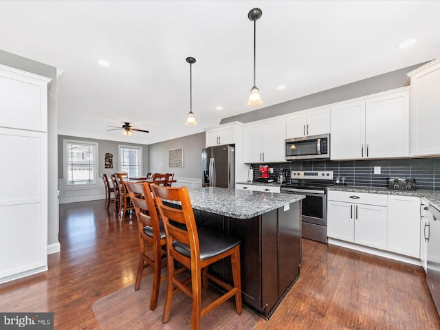 kitchen with white cabinets, light stone counters, tasteful backsplash, and appliances with stainless steel finishes