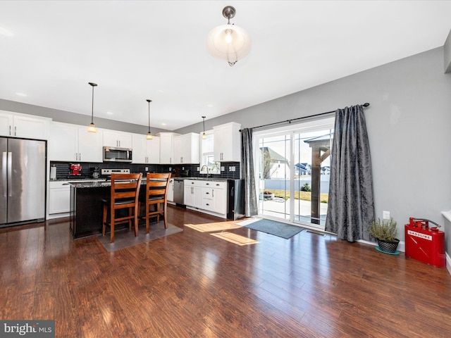 kitchen with decorative backsplash, dark countertops, dark wood-style flooring, and stainless steel appliances