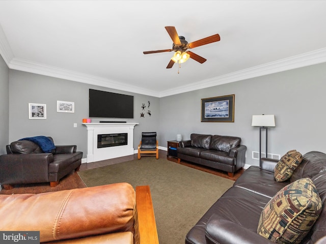 living room with carpet, a ceiling fan, baseboards, ornamental molding, and a glass covered fireplace