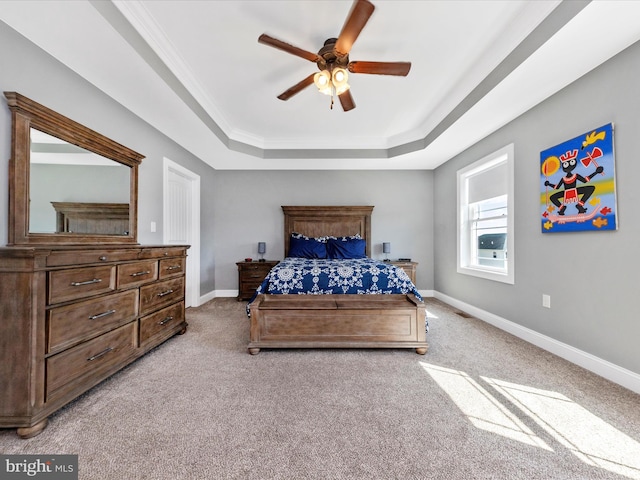 bedroom with a ceiling fan, a tray ceiling, crown molding, baseboards, and light colored carpet