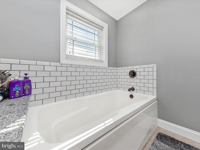 full bath with baseboards, a garden tub, and tile patterned flooring