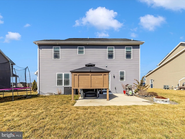 back of property featuring a fire pit, a trampoline, a gazebo, a yard, and a patio area