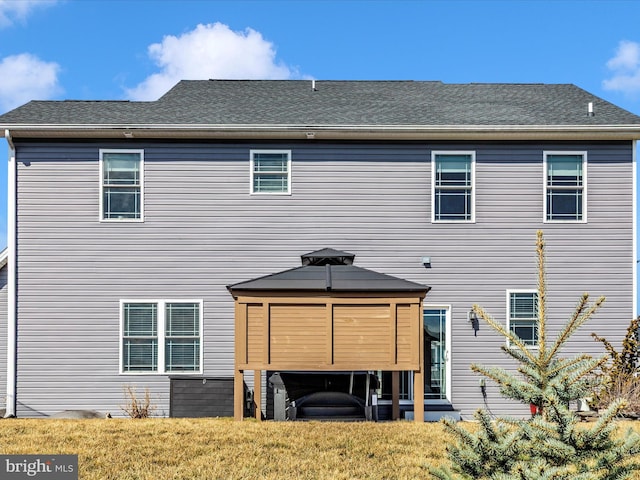 rear view of house with a lawn and a shingled roof