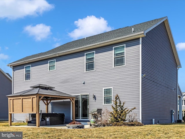 back of property with a gazebo, a fire pit, a lawn, and a patio area