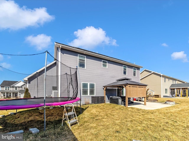 rear view of property with a gazebo, a trampoline, a lawn, and a patio area