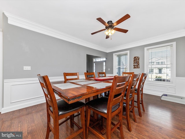 dining room with a wainscoted wall, wood finished floors, a ceiling fan, and ornamental molding