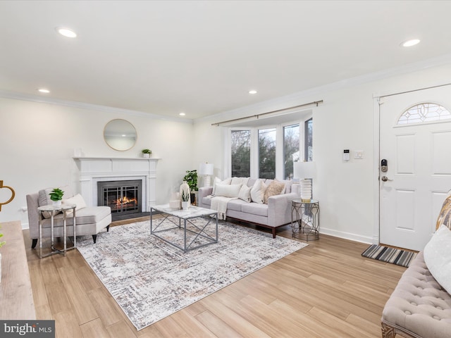 living room with ornamental molding, light wood-style flooring, and baseboards