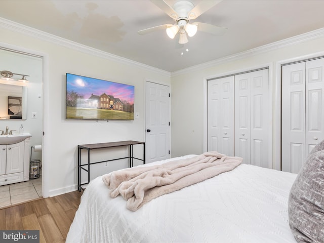 bedroom with baseboards, a ceiling fan, ornamental molding, wood finished floors, and two closets