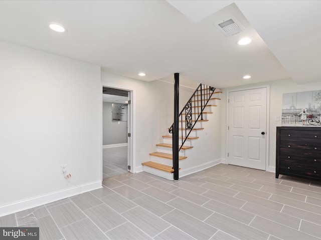 finished below grade area featuring baseboards, stairs, visible vents, and recessed lighting