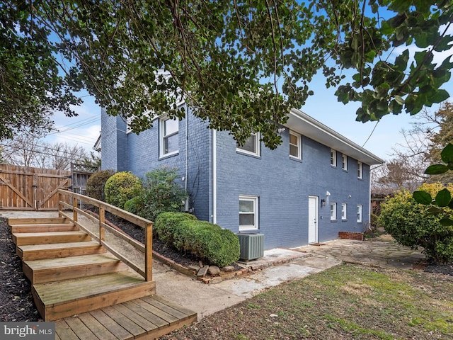 view of property exterior with cooling unit, a patio area, brick siding, and fence