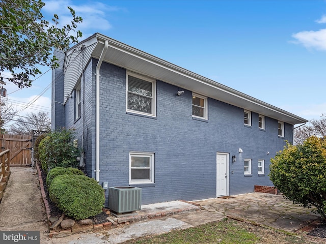 back of house featuring central AC, brick siding, a patio, and fence