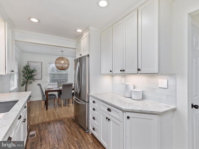 kitchen featuring dark wood-style floors, light stone counters, tasteful backsplash, freestanding refrigerator, and white cabinets