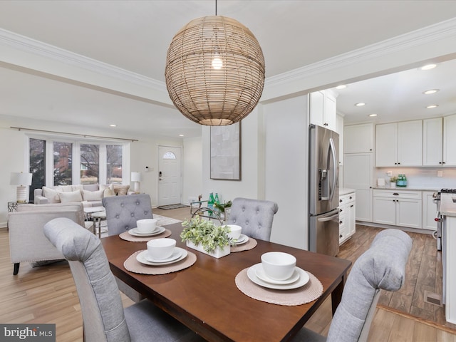 dining area with light wood finished floors, ornamental molding, and recessed lighting