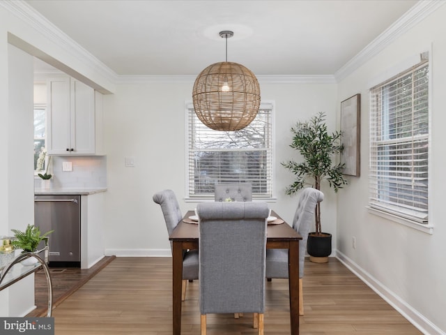 dining area featuring ornamental molding, light wood-style flooring, and baseboards