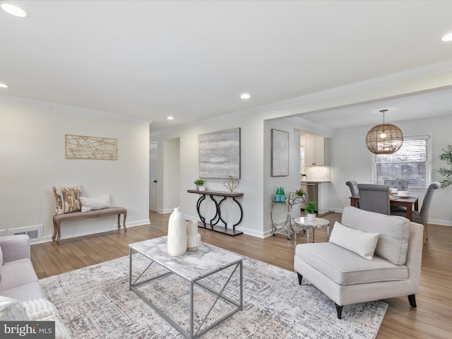 living area featuring baseboards, visible vents, ornamental molding, wood finished floors, and recessed lighting