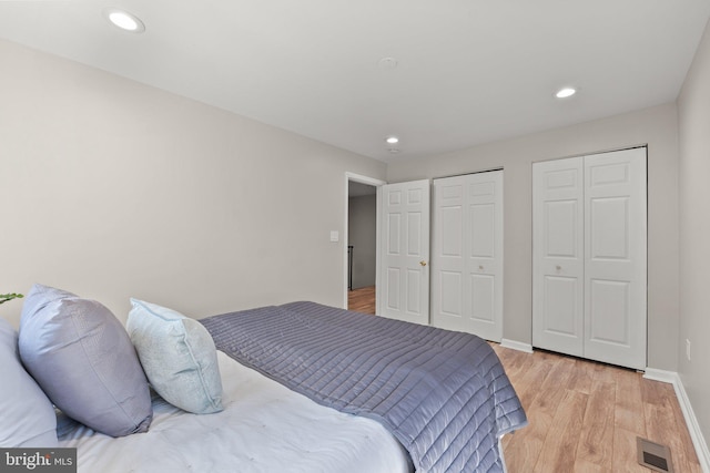 bedroom with light wood-style flooring, recessed lighting, visible vents, baseboards, and two closets