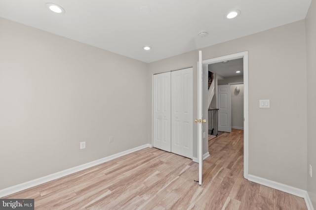 unfurnished bedroom featuring recessed lighting, a closet, light wood-style flooring, and baseboards