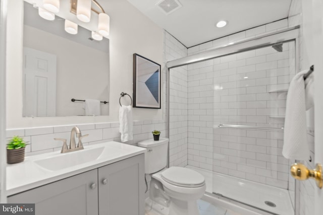 bathroom with a stall shower, visible vents, vanity, and toilet